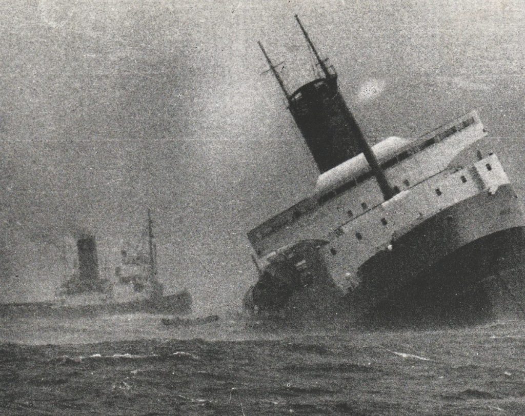 A lifeboat can be seen leaving the stricken Wahine while the tug Tapuhi looms in the background.