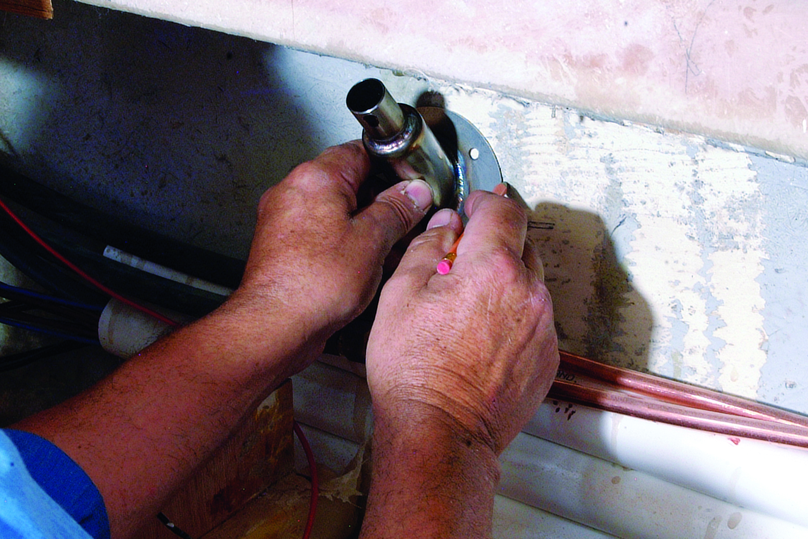 A person uses a handheld torch to perform maintenance work on boat equipment near copper piping in what appears to be an engine compartment or utility area // Photo credit: supplied.
