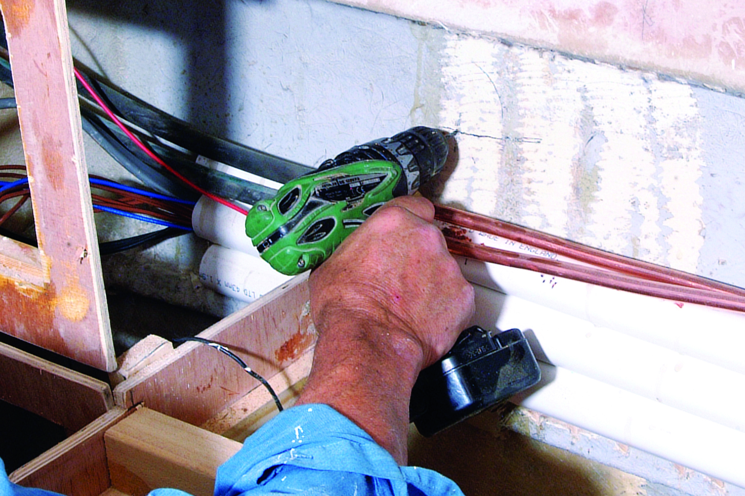 A person's hands work on wiring and electrical components in what appears to be the interior compartment of a boat // Photo credit: supplied.