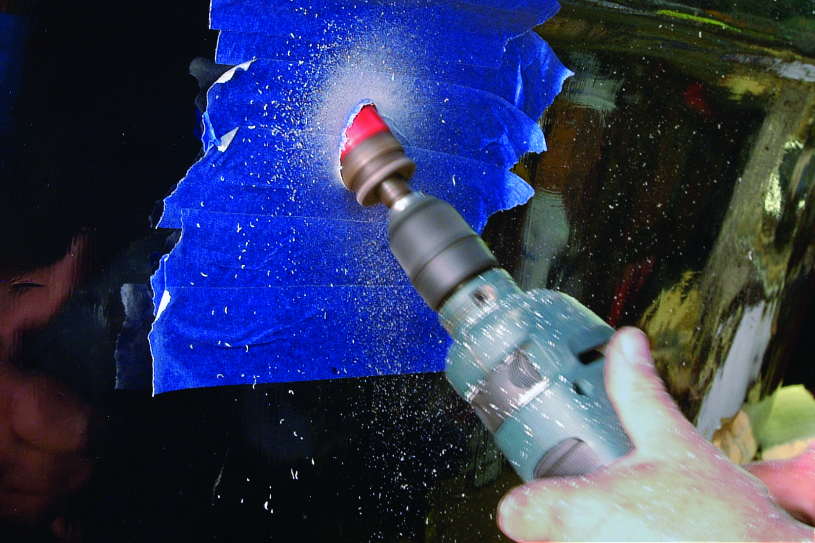 A person uses a spray bottle to clean the hull of a boat that has blue bottom paint // Photo credit: supplied.