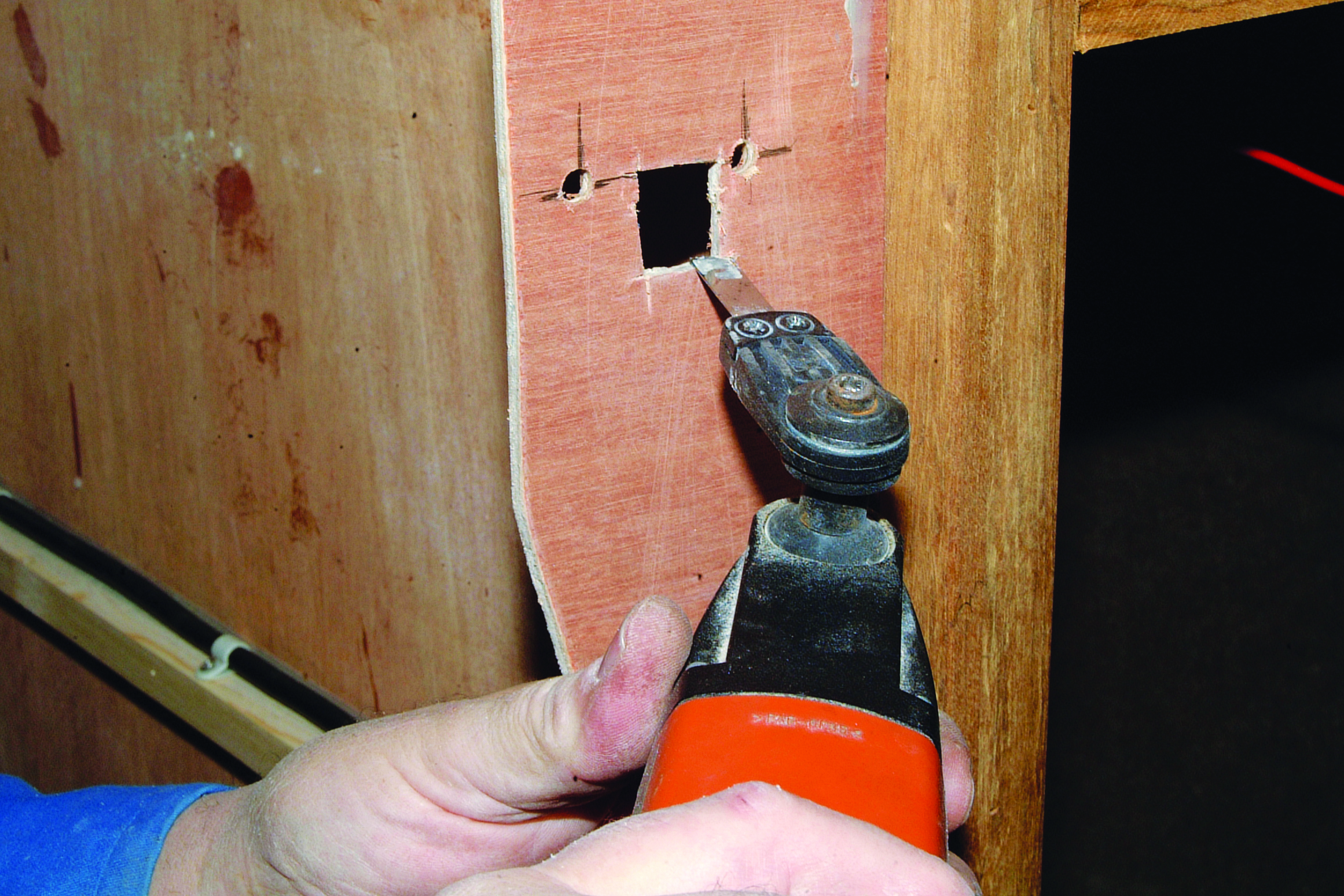 A person uses a power tool to drill or cut into the wooden hull or interior structure of a boat during maintenance or repair work // Photo credit: supplied.