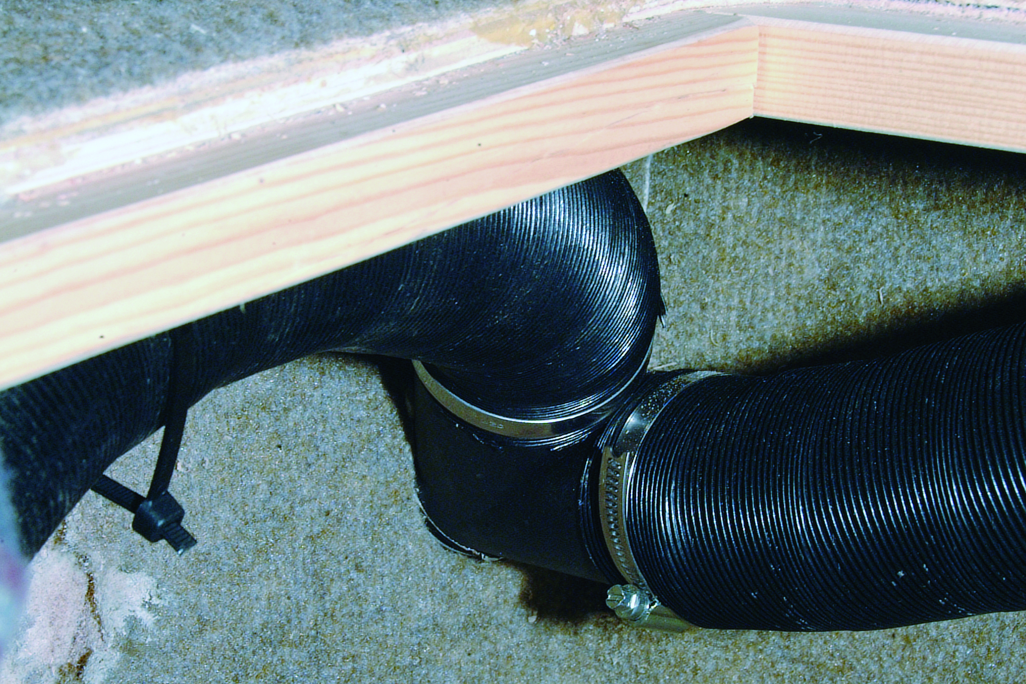 Black corrugated bilge hose with clamps installed in the hull of a boat near the waterline // Photo credit: supplied.