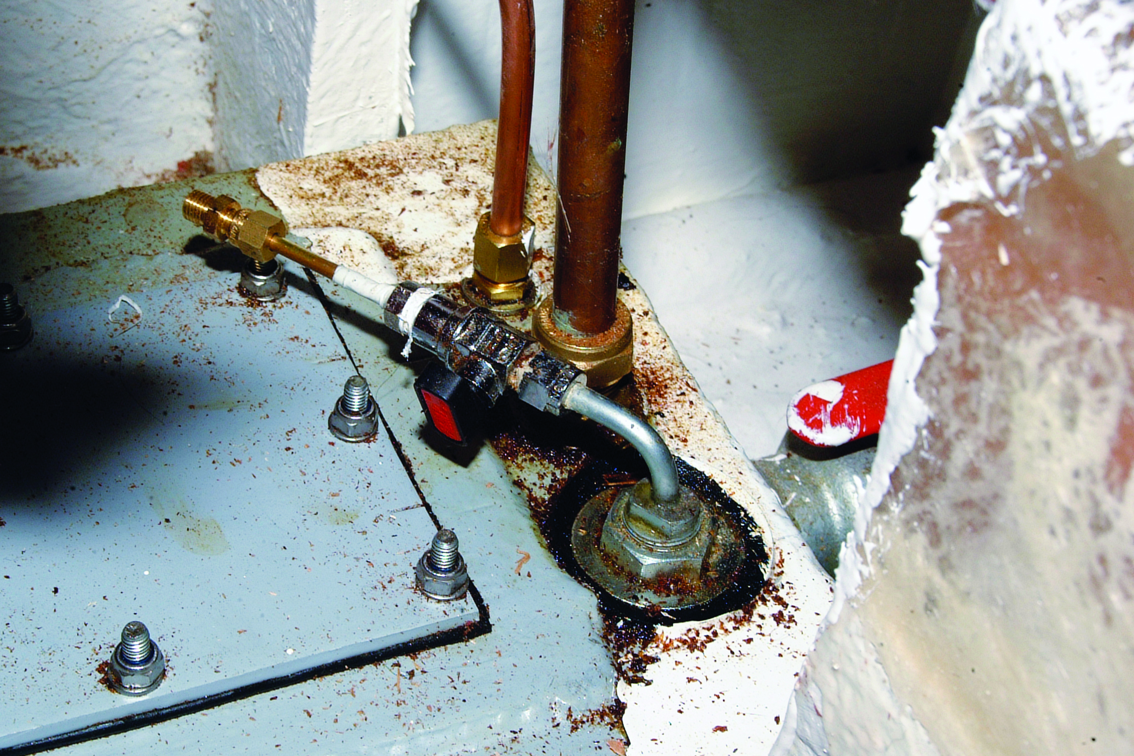 A corroded through-hull fitting with copper pipes and mounting bolts shows significant rust damage in what appears to be a boat's bilge or engine compartment // Photo credit: supplied.
