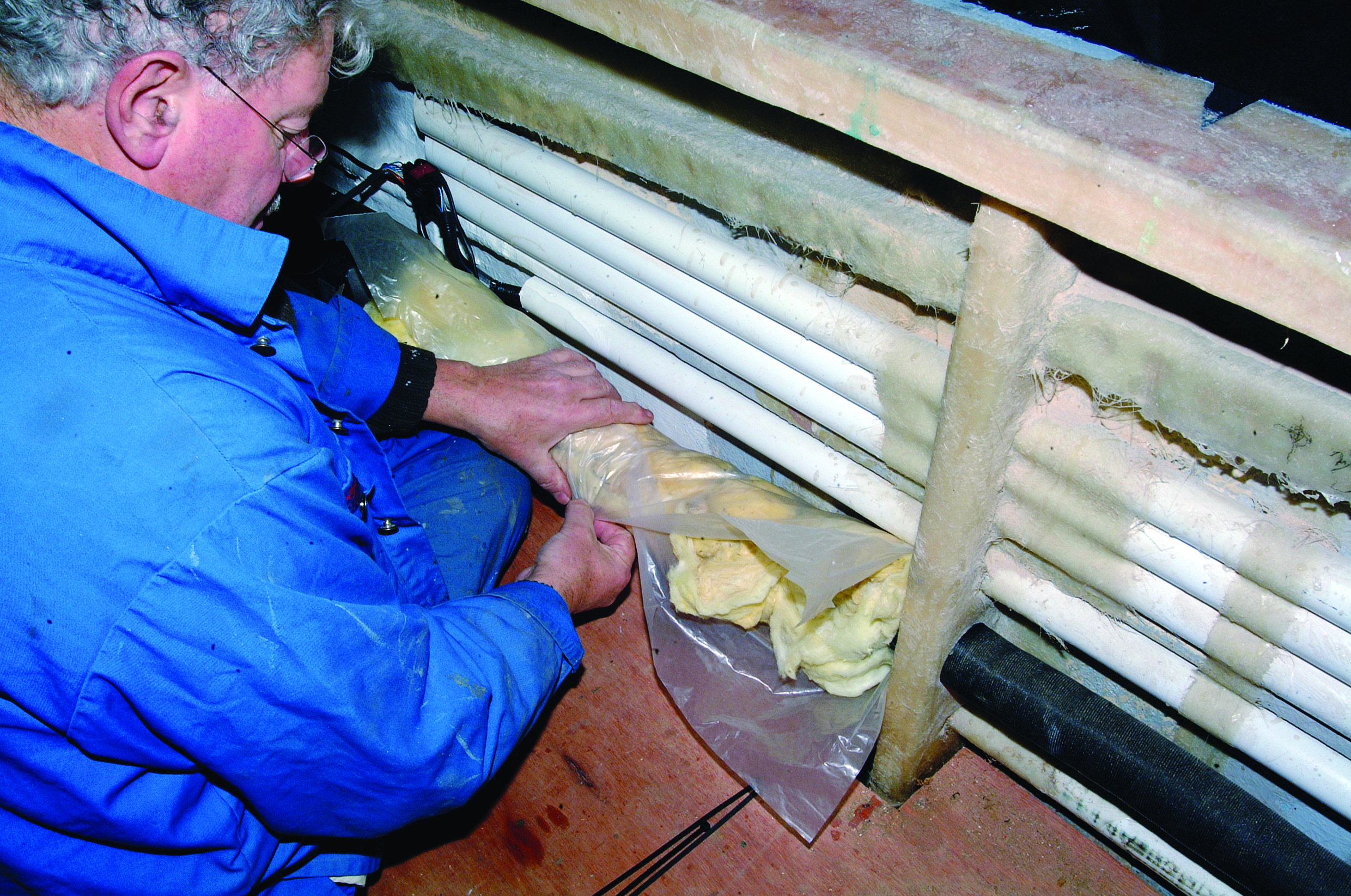 A person in blue protective clothing collects samples from sediment core sections laid out on the deck of a research vessel // Photo credit: supplied.