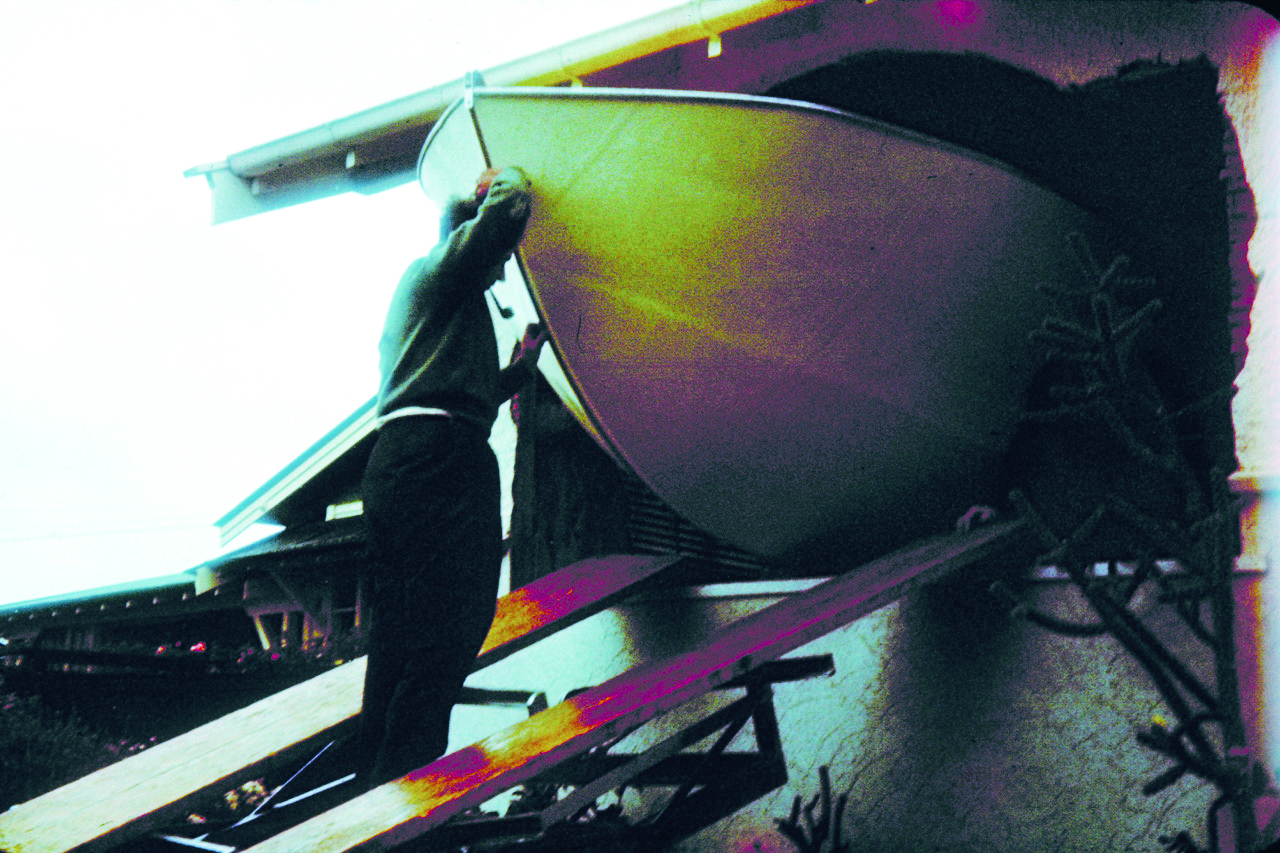 A person operates a boat from the helm position while navigating on the water, captured with artistic color effects that create purple and green tonal shifts across the scene // Photo credit: supplied.