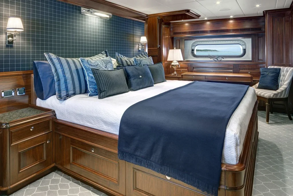 The owner’s suite spans the yacht’s full beam aft, with rich timber cabinetry and blue accents around the berth - Encore superyacht // Photo courtesy McD Yachts