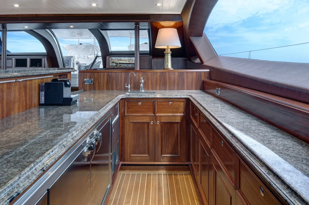 Timber cabinetry and stone benchtops frame the saloon bar, equipped for entertaining family and friends aboard - Encore superyacht // Photo courtesy McD Yachts