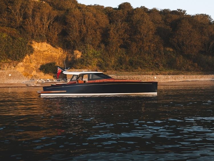 Warm evening light picks out the P50’s low profile, dark hull and varnished timber detailing. // Photo courtesy Spirit Yachts